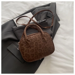 Detail of faux suede leopard print handbag texture and silver hardware on a gray blazer
