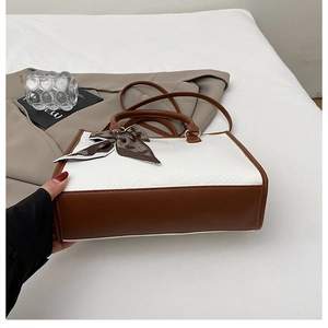 Détail du sac à main serpent blanc avec poignées brunes et foulard en soie décoratif