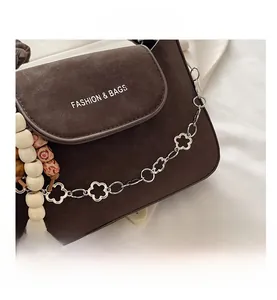 Close-up of retro brown shoulder bag with flower metal chain and wooden bead details