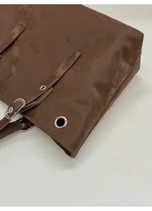 Macro detail of dark brown tote bag showing durable matte texture and silver eyelets