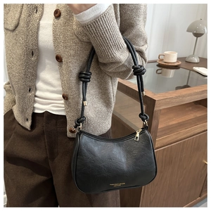 Detail of black matte leather hobo bag with knotted shoulder strap and metal hardware