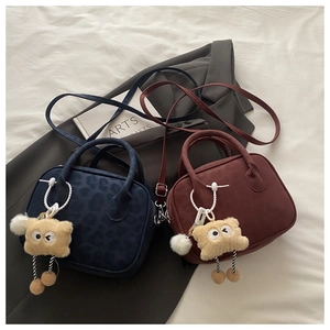 Detail of retro suede Boston bags in navy and burgundy with cute monster charms