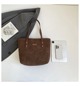 Suede textured brown tote bag detail with metal logo and sleek dark handles