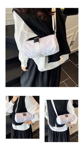 Detail of minimalist white cylinder crossbody bag with durable nylon strap and buckle