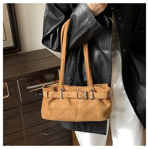 Brown suede shoulder bag with belt detail and silver buckle shown on a model