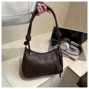 Detail of dark brown vintage faux leather shoulder bag with unique knotted rope handle