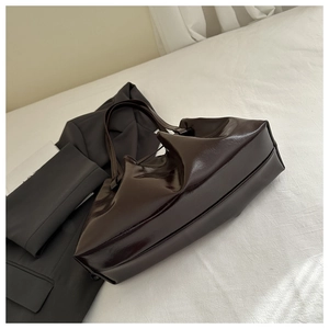 Detail of dark brown glossy tote bag featuring wax leather texture and folded design