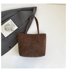 Detail of dark brown suede tote bag with leather handles and minimalist commute style