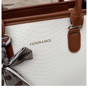 Détail de la texture serpent blanc du sac avec foulard en soie et logo doré