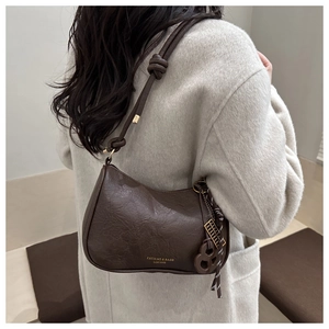 Detail of a brown vintage leather shoulder bag with a knotted strap and abacus charm