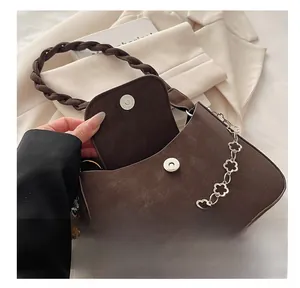 Detail of dark brown matte bag featuring a magnetic clasp and floral silver chain