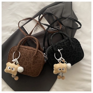 Detail of faux fur leopard print handbags in brown and black with plush charms