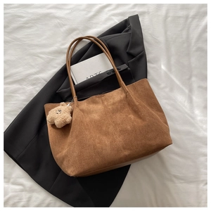 Détail d'un sac cabas marron mat avec fines bretelles et pendentif ours en peluche