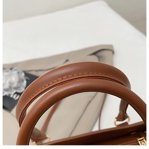 Détail de la poignée de sac en similicuir marron avec surpiqûres et anneaux dorés