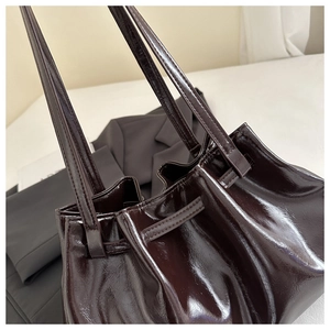 Close-up of shiny pleated leather tote bag showing smooth glossy texture and drawstring detail