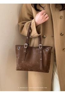 Detail of dark brown retro shoulder bag featuring metallic buckles and vintage texture