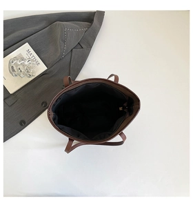Detail view of the spacious black fabric interior and zipper pocket in a brown tote bag