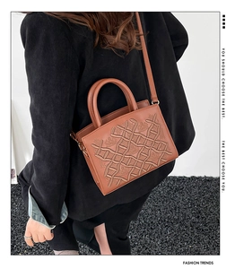 Brown embroidered handbag with woven texture shown on shoulder for a stylish commuting look