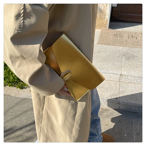 Detail shot of a minimalist gold metallic envelope clutch with an oval metal clasp closure