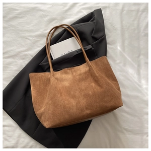 Sac cabas marron en daim avec blazer noir sur fond blanc minimaliste