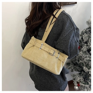 Close-up of yellow suede shoulder bag with adjustable belt buckle and silver metal hardware