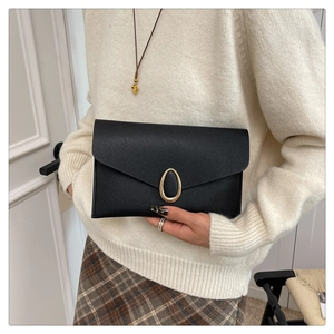 Detail of black Saffiano leather envelope clutch with a golden oval metal buckle