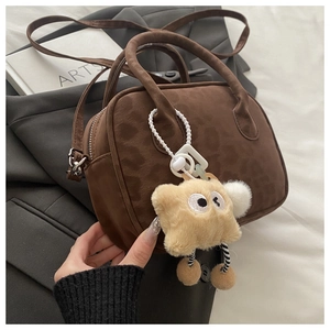 Close-up of leopard pattern dark brown suede handbag with a plush monster charm