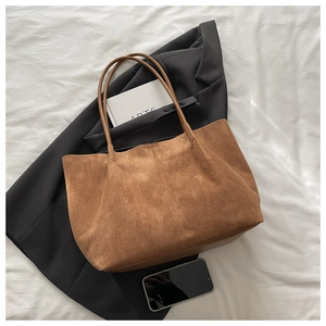 Vue à plat d'un sac cabas en daim marron avec de longues anses sur tissu blanc
