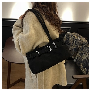 Détail du sac à épaule en daim noir avec ceinture décorative et boucle argentée sur modèle