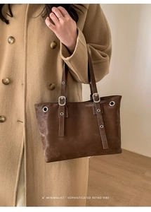 Close-up of vintage dark brown tote bag with matte leather texture and silver buckle