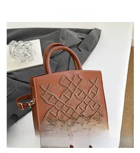 Detail of dark brown handbag showing intricate crown embroidery and sleek patent finish
