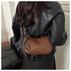 Brown leather half-moon shoulder bag featuring metal charms and braided rope detail