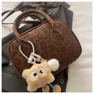 Close-up of brown leopard print handbag with a cute plush monster charm detail
