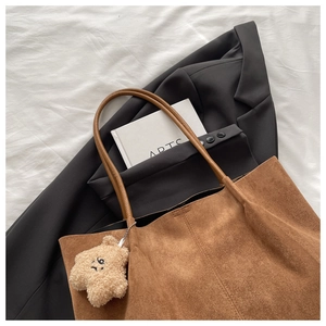Détail du cabas en daim marron avec anses en cuir et un pendentif étoile en peluche