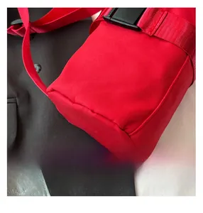 Detail of red cylindrical travel bag showing high-quality stitching and durable strap buckle