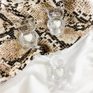 Detailed view of three transparent resin bears with white heart motifs on textured fabric