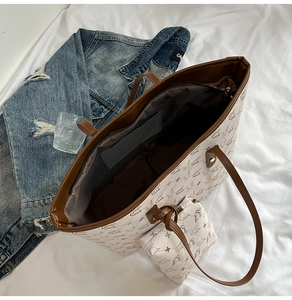 Detail view of large tote bag with bird print pattern, leather handles and inner pouch