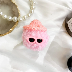 Pink plush doll phone grip with sunglasses and hat displayed on white fabric and pearls