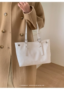 Dettaglio della borsa tote bianca con fibbia in metallo e occhielli dal design minimalista