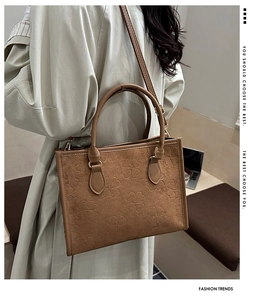 Dettaglio della borsa tote in pelle scamosciata marrone con motivi a trifoglio a rilievo