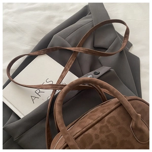 Detailed view of brown leopard print suede crossbody bag on a grey blazer outfit