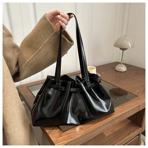 Close-up of black glossy pleated tote bag with fine stitching and sleek handles