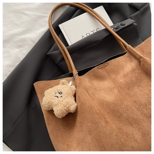 Grand sac cabas en daim marron avec pendentif étoile en peluche sur un lit