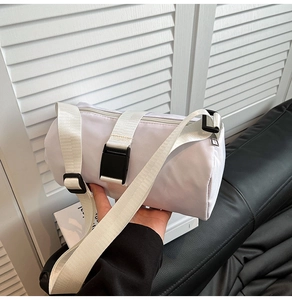 Detail of white cylinder nylon crossbody bag with adjustable strap and plastic buckle