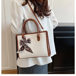 Détail du cabas en cuir beige à motif serpent avec poignées brunes et foulard décoratif