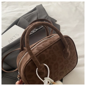 Detail of dark brown leopard print suede Boston bag with plush bead charm and silver zipper