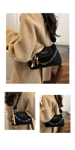Detail of black suede bag with woven strap, floral chain, and colorful wood bead tassel