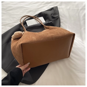 Détail du sac cabas en daim marron avec un pendentif en peluche d'ours décoratif