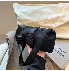 Detail of black nylon cylinder bag with adjustable strap and buckle closure