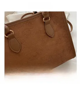 Primo piano della borsa tote in pelle scamosciata marrone con motivi a quadrifoglio impressi
